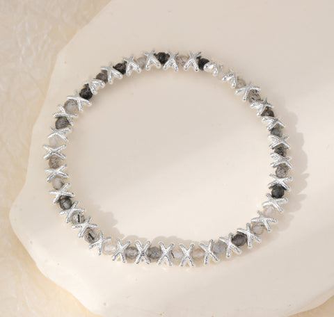 Neutral stones sit between silver plated X charms on this stretch bracelet